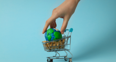 Mão colocando um planeta dentro de um mini carrinho de supermercado.